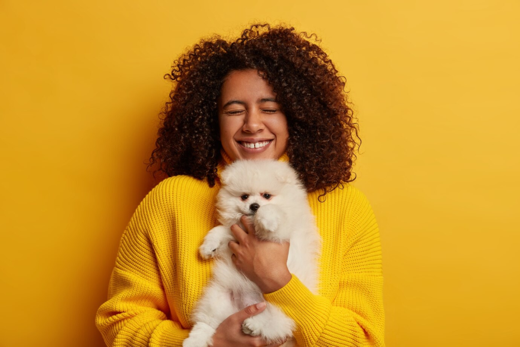 Mulher feliz segurando um filhote de cachorro no colo.